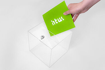 Transparente Wahlurne, darüber ein Hand mit einem grünen Zettel und HTW Logo © HTW Berlin
