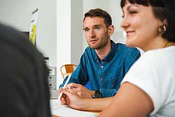 Two students engage in a focused discussion in a small group setting.