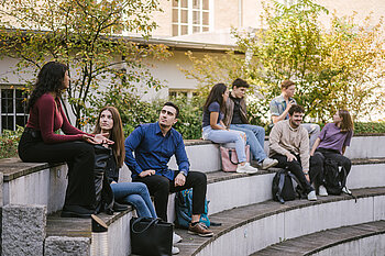 Students sit on outdoor steps and chat in a relaxed atmosphere on campus.