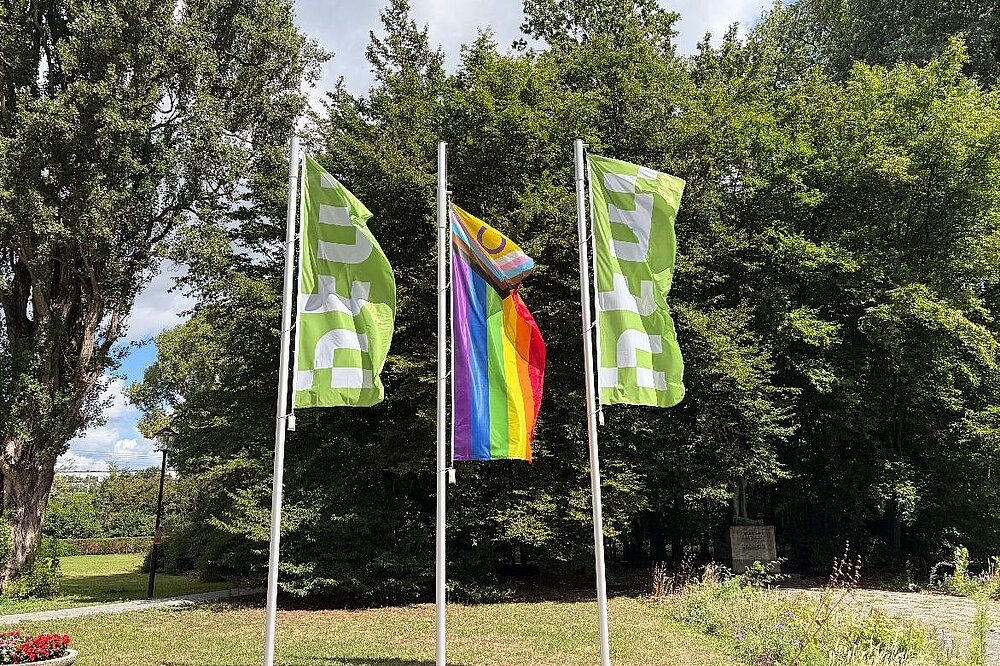 Die inter*-inklusive Progress-Pride-Flagge zwischen zwei HTW-Flaggen am Campus Treskowallee © HTW Berlin/Anja Schuster